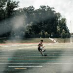 man in red shirt and black shorts riding on black skateboard on gray concrete road during